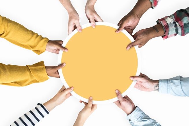 diverse hands holding a yellow circle