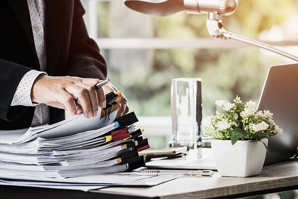 a man counting a stacks of documents on a desk in a bright office