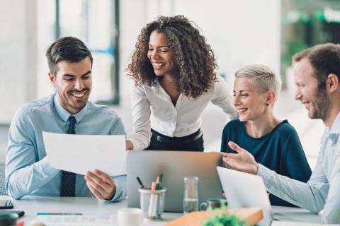 two women and two men smiling and collaborating at work